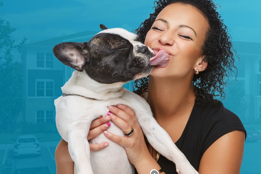 Woman holding dog and smiling while he tries to lick her face